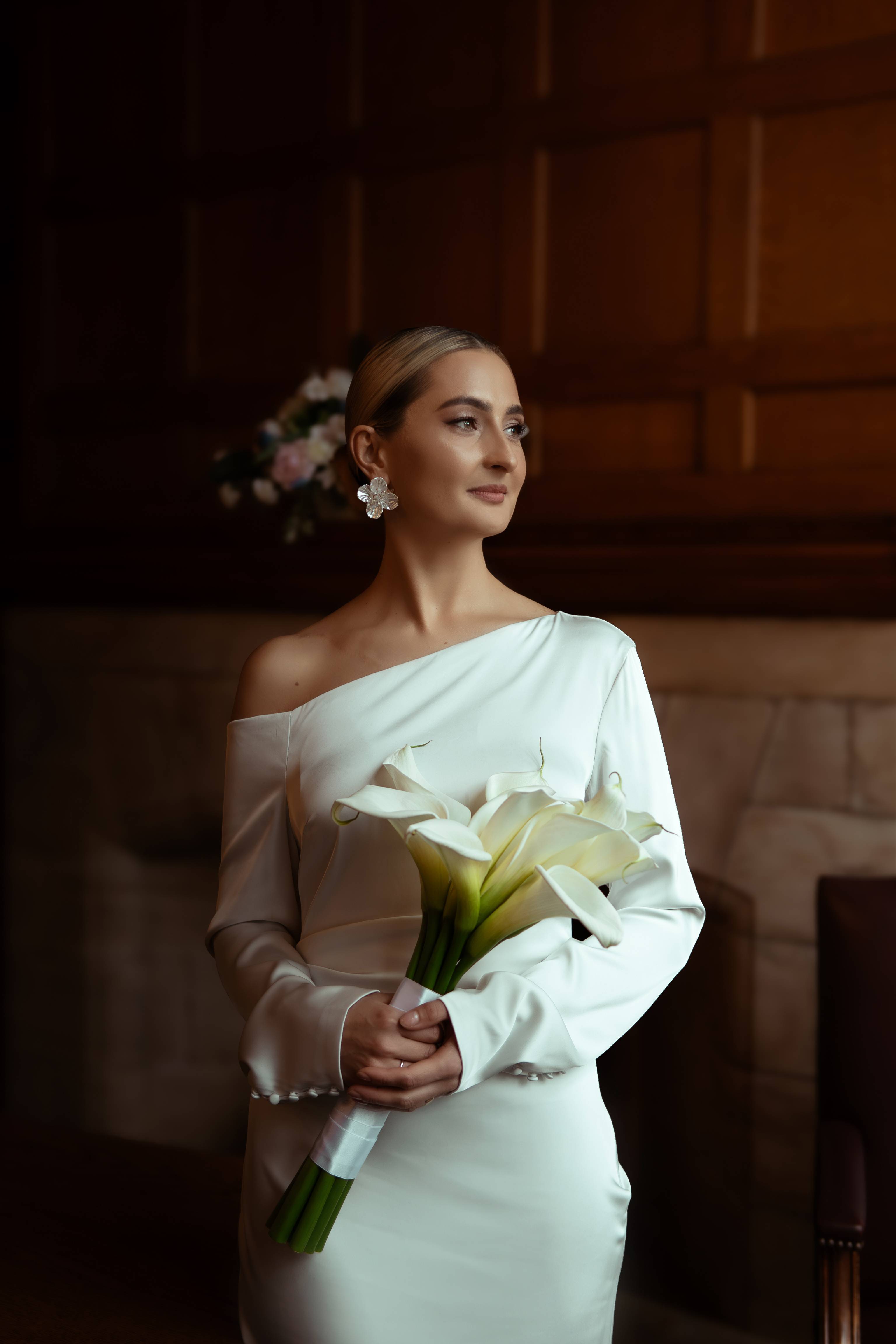 Elegant bride holding a bouquet of calla lilies in soft light