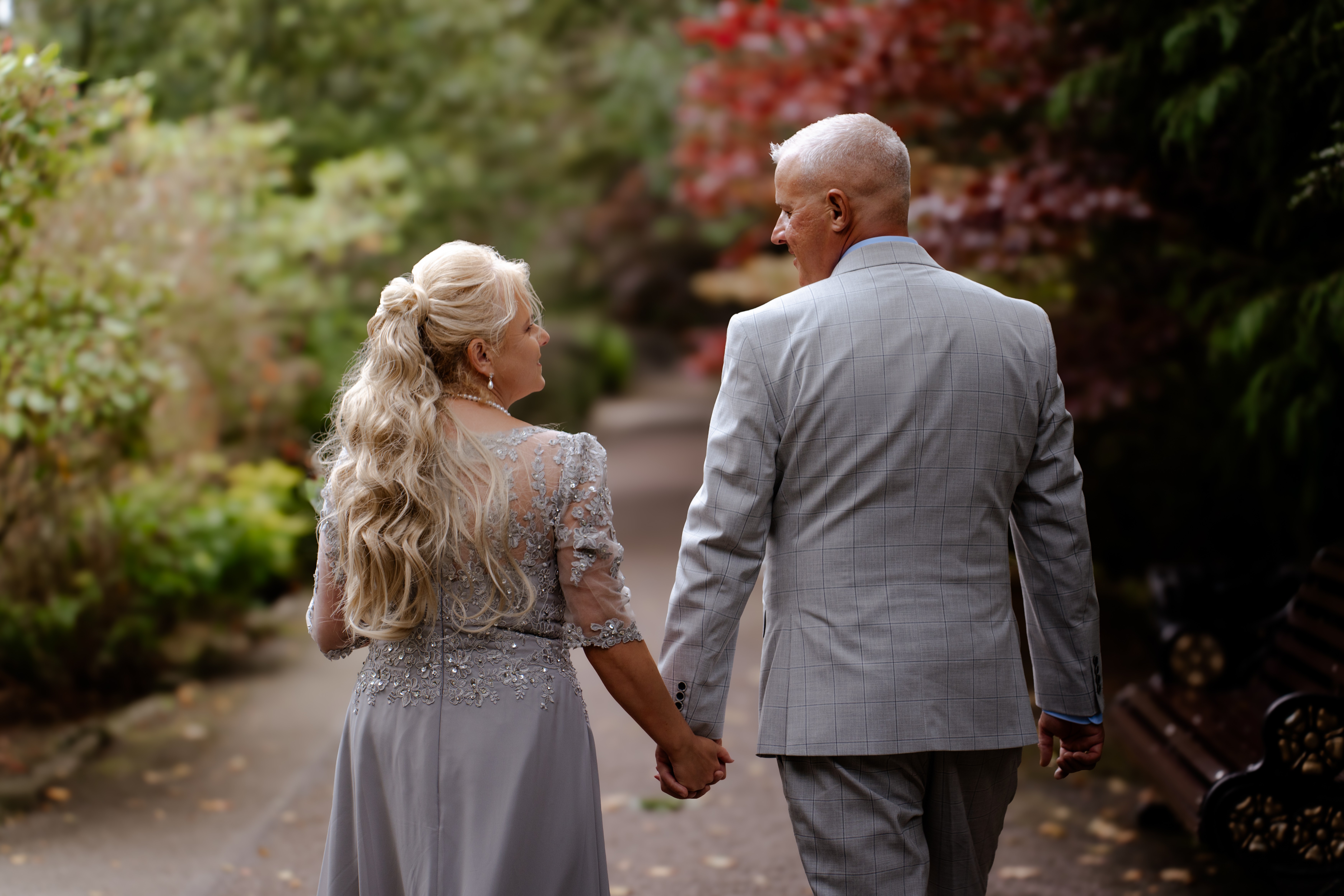 Couple walking hand in hand along a garden path